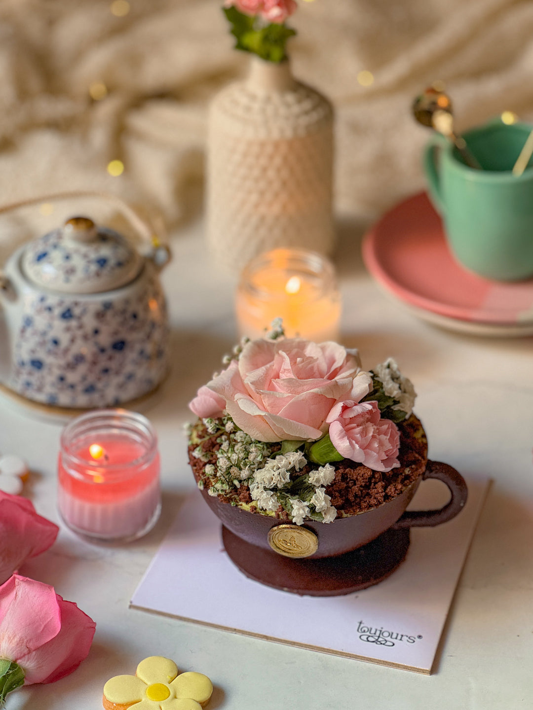 Dessert Teacup with flowers, candles, and teapot on a table with a soft focus background